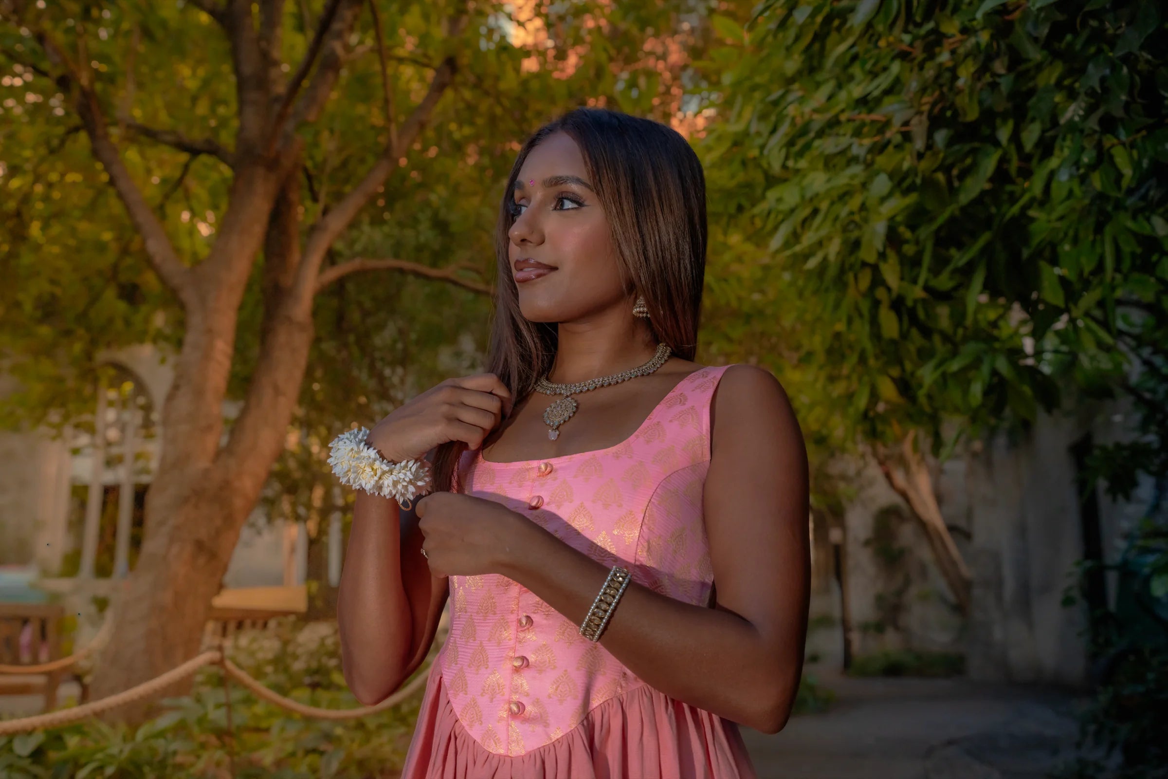 A woman in the Meeka collection's peach Thalia dress beneath sunlit trees
