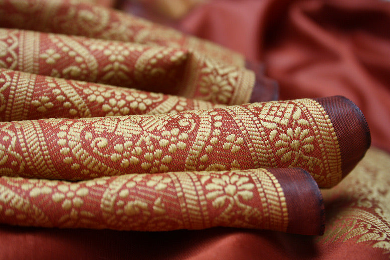 Folds of rust silk with a woven gold zari paisley border